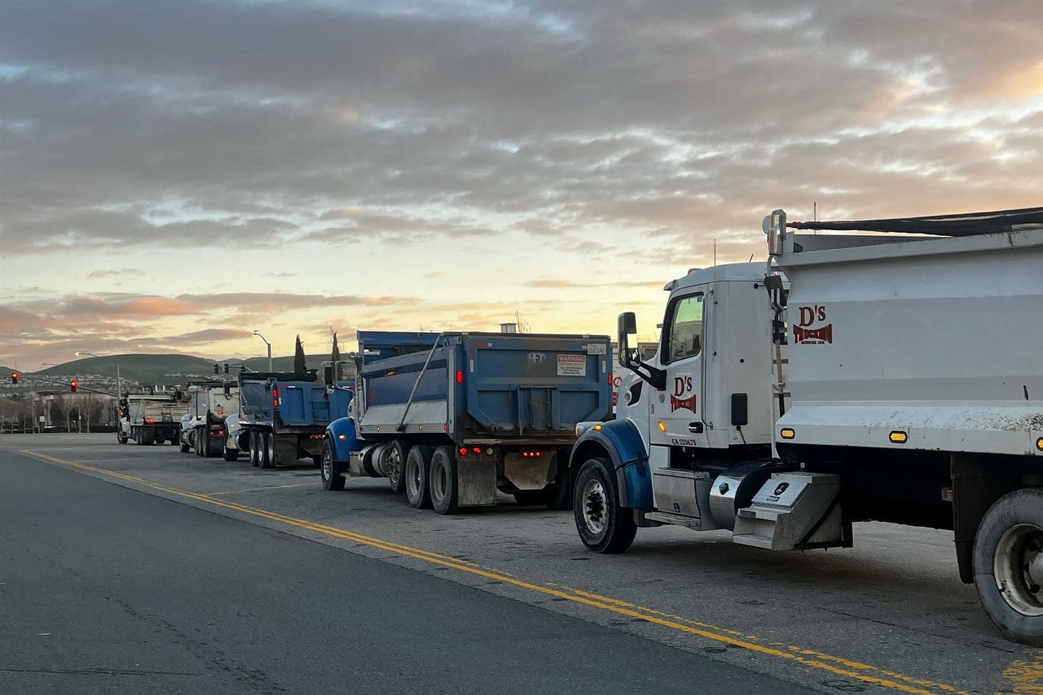D’s trucks lined up at first light, East Bay hills behind