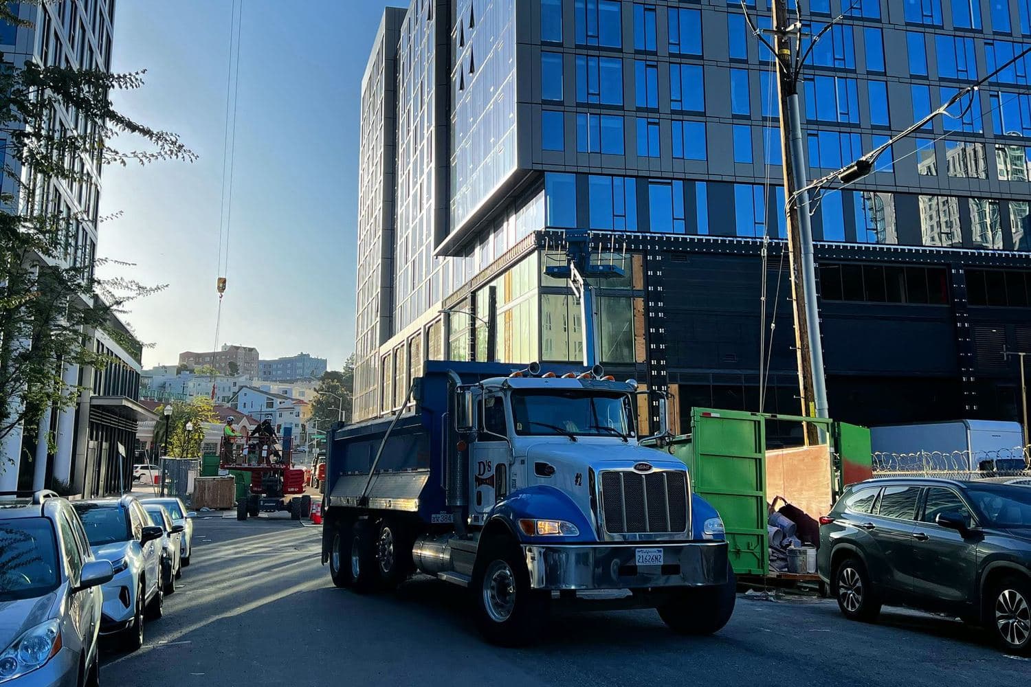 A D’s dump truck on an Oakland infill street beside a tower under construction